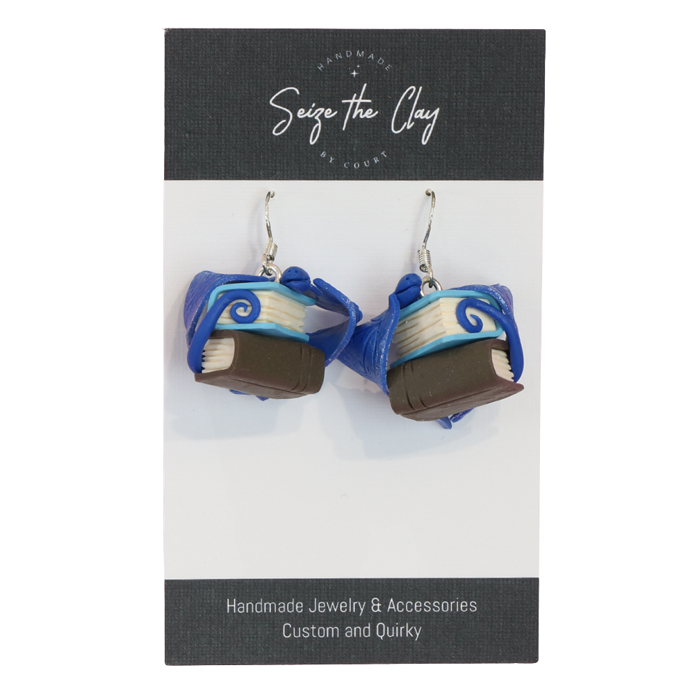 Book-shaped earrings on a 'Seize the Clay' branded card