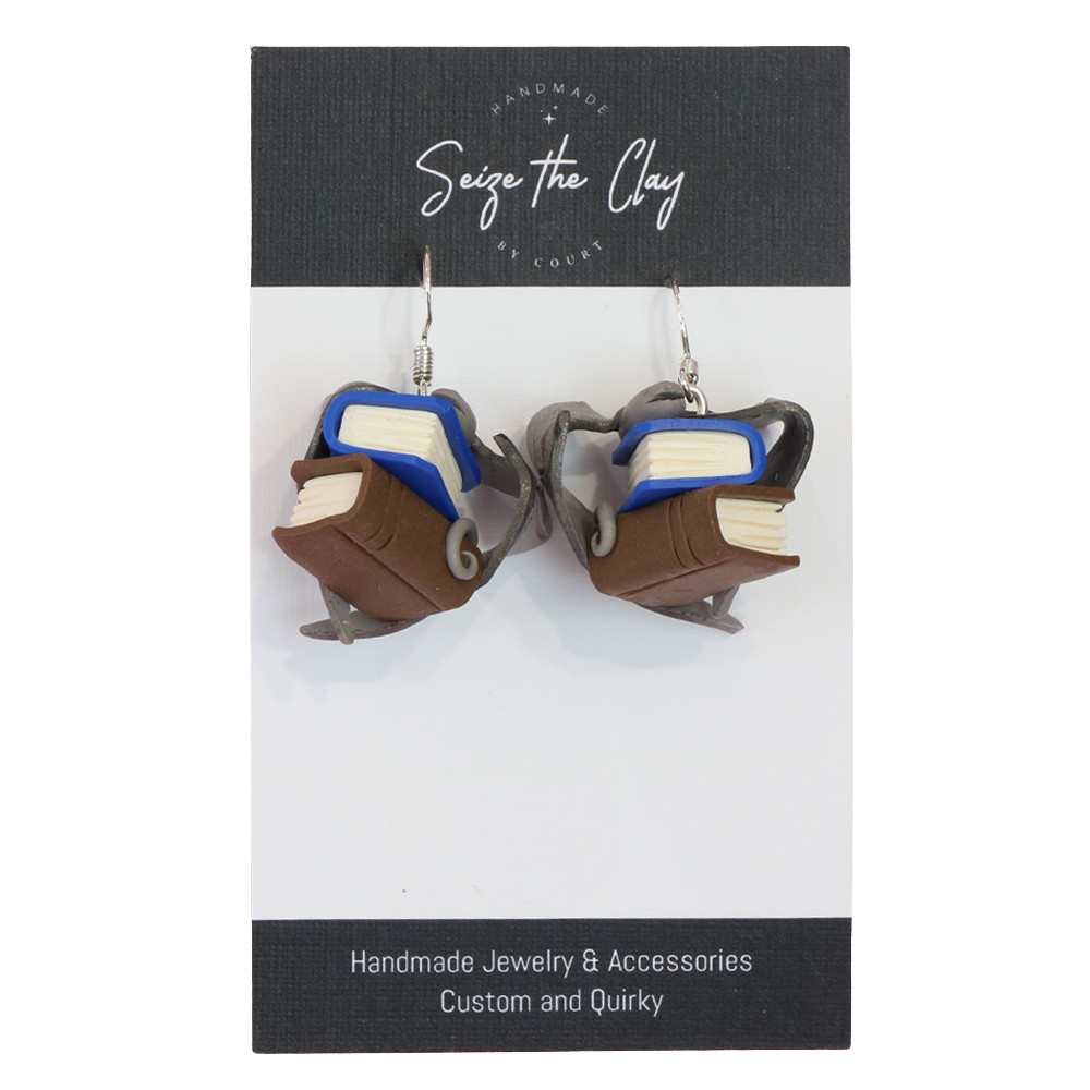 Book-shaped earrings on a 'Seize the Clay' branded card