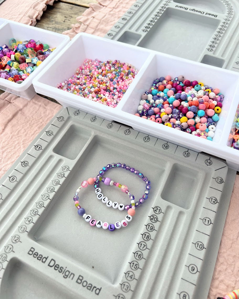 Bead design board with colorful beads and a bracelet on a wooden surface