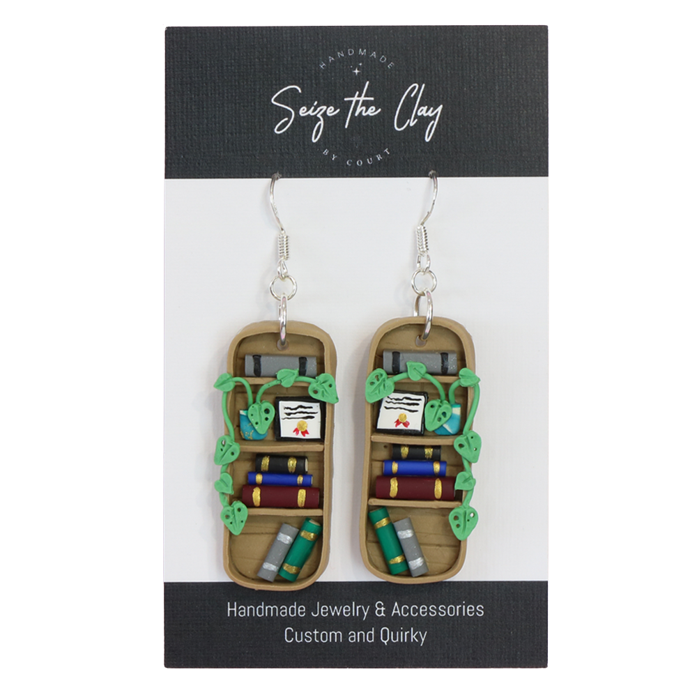 Handmade bookshelf earrings on a 'Seize the Clay' branded card.