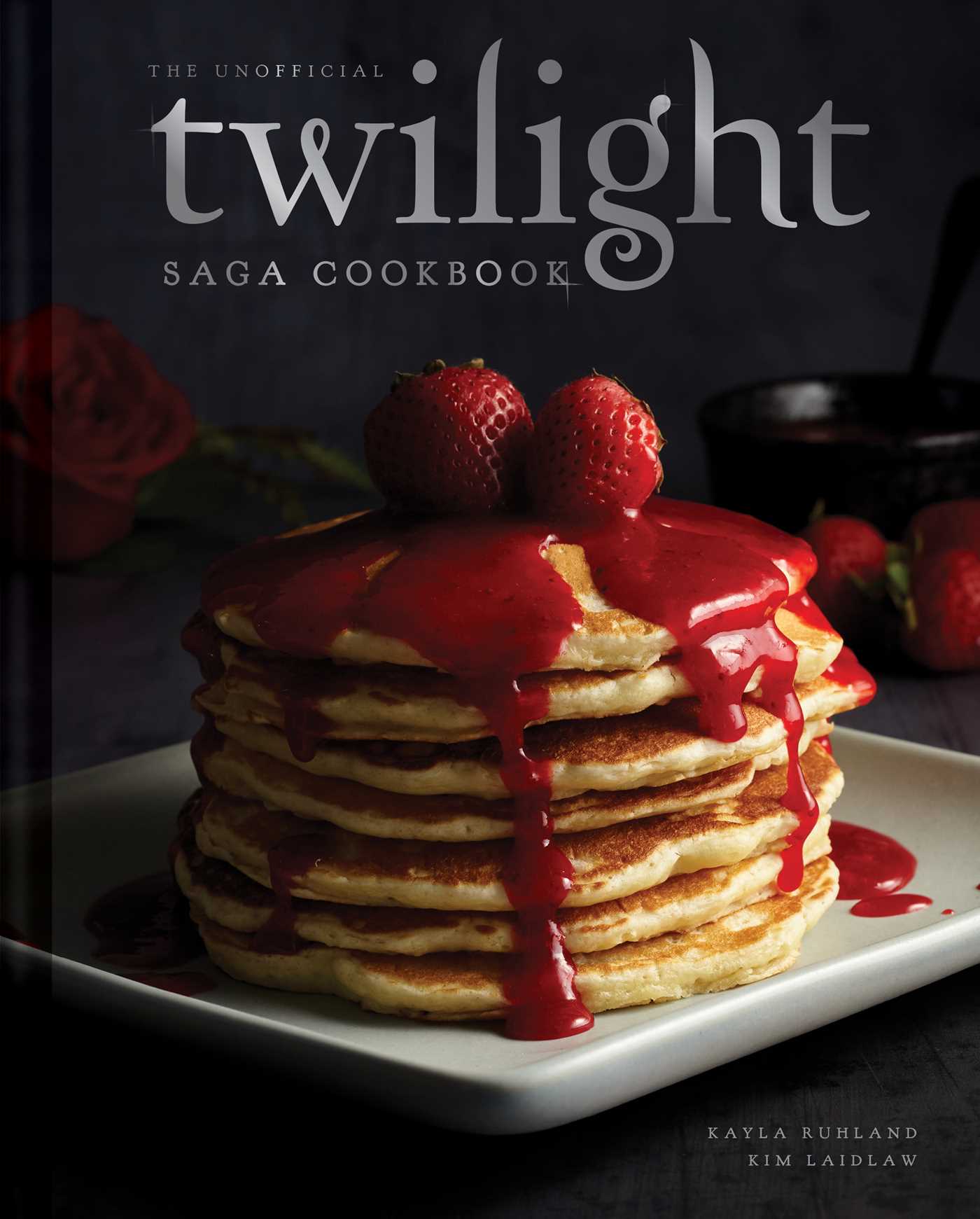Book titled 'The Unofficial Twilight Saga Cookbook' with a stack of pancakes and strawberries on a dark background.